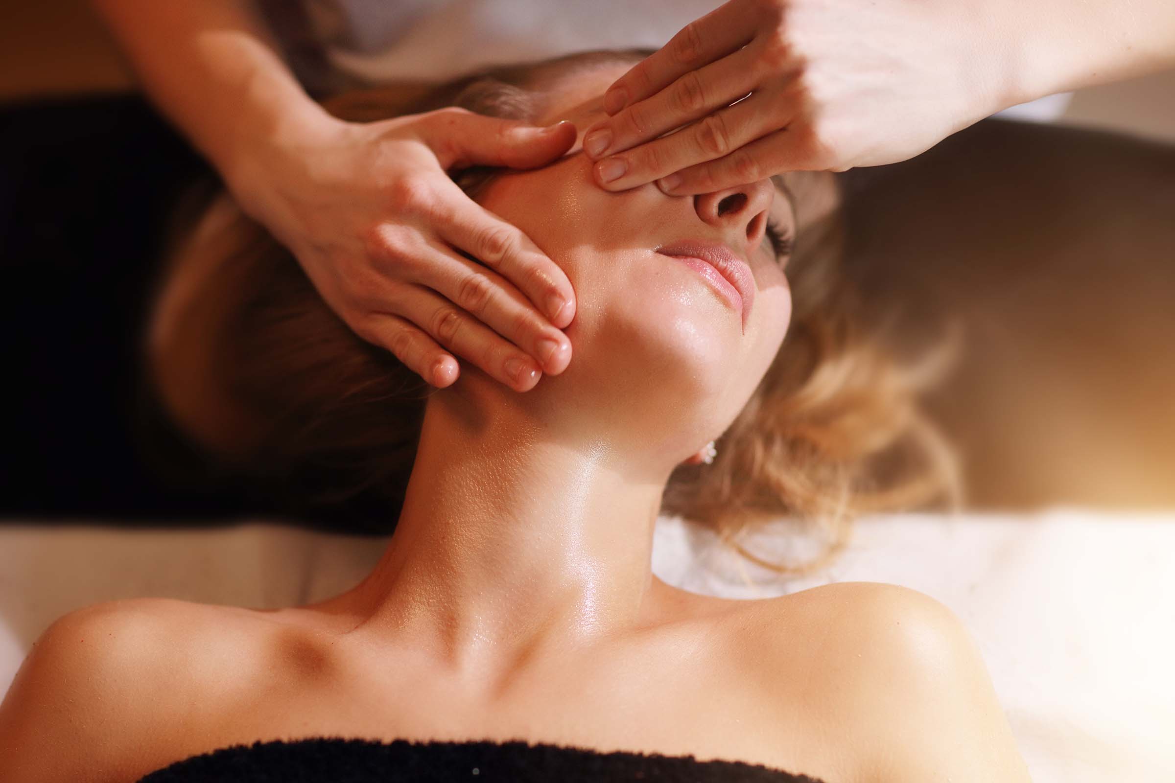 happy woman having face massage in spa salon BB2ASVD